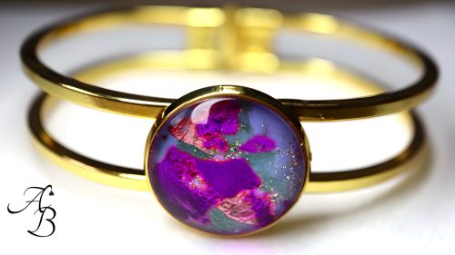 Bracelet en acier doré avec cabochon de verre mauve, vert et fuchsia par Aline B Création.