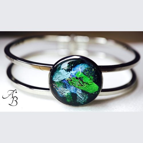 Bracelet cabochon en acier avec un cabochon en verre aux teintes vertes et bleues.