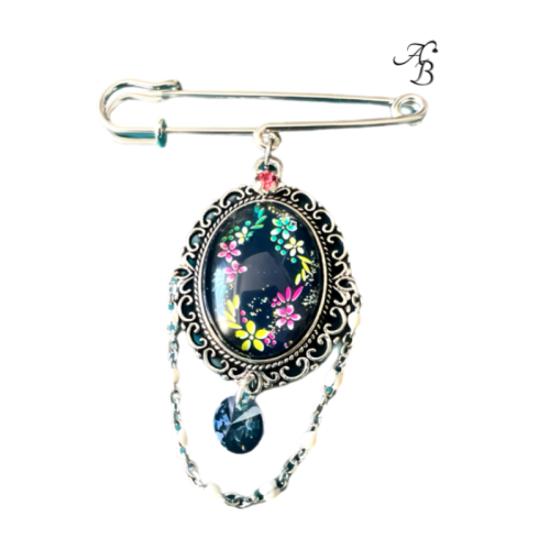 Broche – Danse florale sous les étoiles en verre peint à la main, avec cabochon bleu marine et motifs floraux colorés, création artisanale Aline B Création.