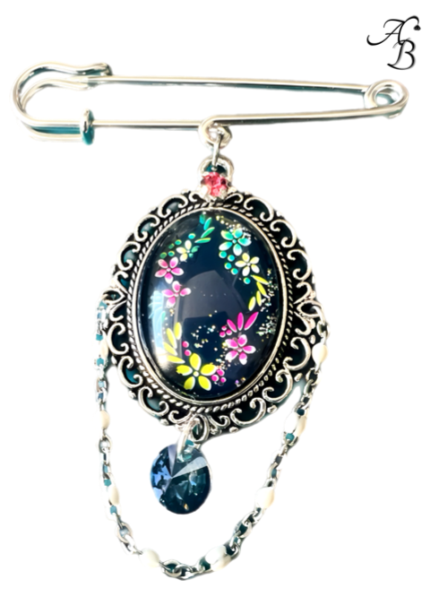 Broche – Danse florale sous les étoiles en verre peint à la main, avec cabochon bleu marine et motifs floraux colorés, création artisanale Aline B Création.