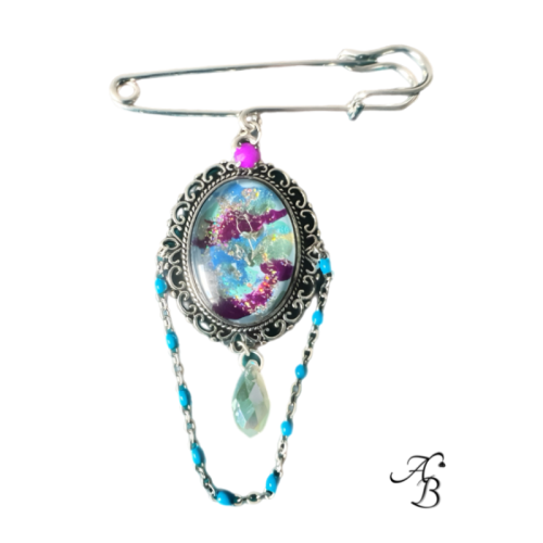 Broche – L’ombre d’une rose, cabochon peint à la main avec reflets violets et chaîne décorative.