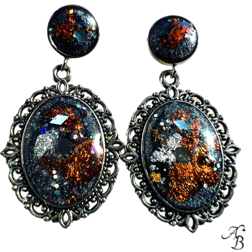 Boucles d’oreilles clous Héritage braisé en résine noire et cuivrée avec paillettes scintillantes, monture baroque argentée.