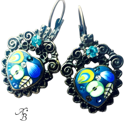 Boucles d’oreilles dormeuses Apple heart en métal argenté, cœur émaillé bleu avec motifs floraux et incrustations de cristaux colorés.