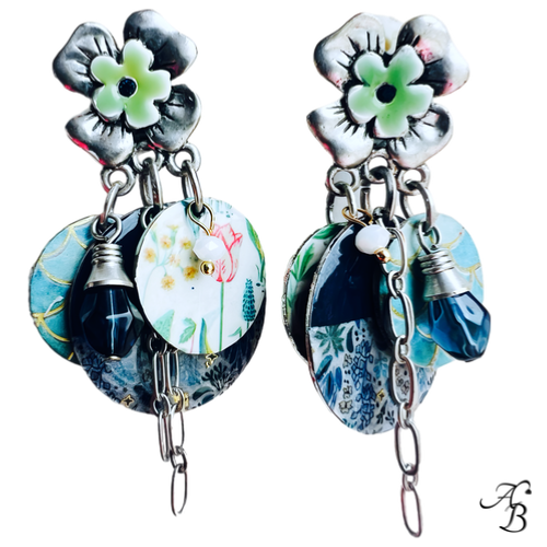 Boucles d’oreilles clips Magic garden en alliage argenté, décor floral et médaillons peints à la main avec chaînes et gouttes de verre bleu.