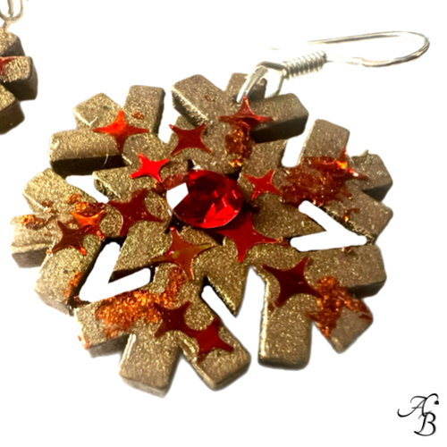 Boucles d’oreilles Flocon doré en bois mordoré avec cristal rouge et paillettes scintillantes, création artisanale Aline B Création.