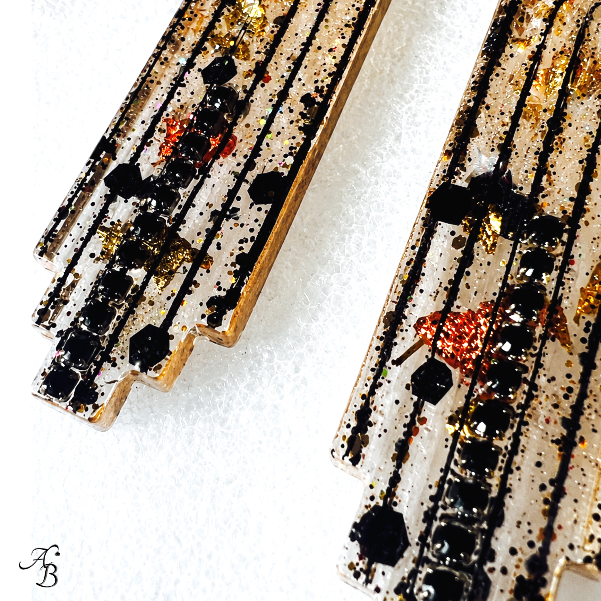 Boucles d’oreilles clous Resin’ Longue dark en résine nervurée avec feuilles métalliques dorées, cuivrées et noires, paillettes dorées et chaînette cristal noir - Aline B Création.